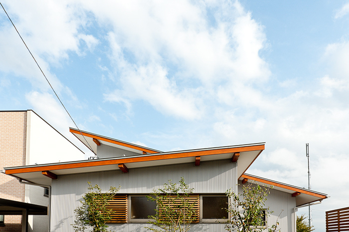 屋根：2枚の片流れ屋根を交差し伸びやかに_ガルバリム鋼板小波_木製格子面格子エステックウッド_植栽_片流れ屋根